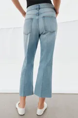 Jeans de tiro medio con corte flare y largo cropped. Presentan diseño de cinco bolsillos, cierre frontal con cremallera y botón, raya planchada en el delantero y bajo desflecado con acabado evasé.