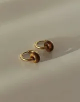 Aros abridores de acero quirúrgico dorado con dije colgante en forma de piedra natural marrón con efecto jaspeado.