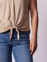 Blusa color beige de modal con escote en V, abertura central con botones y ruedo anudado. Marca French Laundry.