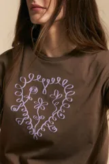 Remera de manga corta color marrón, con estampado central de corazón en color lila.