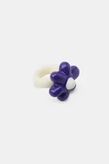 Pack de dos anillos de resina multicolor. Uno de los anillos presenta un diseño liso en color fucsia con una aplicación esférica amarilla en contraste, mientras que el otro cuenta con una base blanca y un aplique en relieve con forma de flor en tonos azul y blanco.