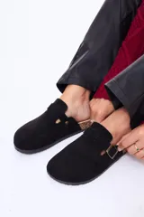 Zueco de gamuza color negro con diseño de punta redonda, ajuste mediante tira con hebilla metálica y suela de corcho.