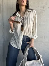 Camisa a rayas verticales color crudo y gris, de corte holgado y mangas largas con puños abotonados.