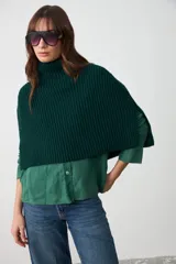 Capita de punto acanalado en color verde oscuro, con cuello alto y diseño corto que cubre hombros y pecho.