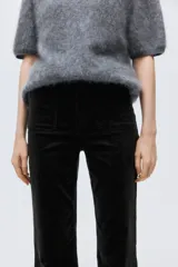 Pantalón acampanado de pana color negro, de tiro alto, con cierre de botón y bolsillos de parche delanteros y traseros.