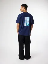 Remera azul marino de manga corta, con calce holgado y estampado gráfico geométrico en la espalda con diseño de cruces en tonos celestes y blancos.