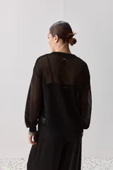 Sweater calado de punto negro, con cuello redondo y mangas largas, de diseño liviano ideal para superposiciones.