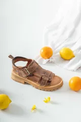 Sandalias de cuero marrón con tiras anchas y hebillas ajustables. Suela gruesa con diseño dentado.