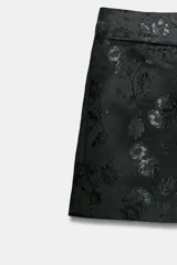 Shorts mini de tiro bajo confeccionados en tejido jacquard con diseño floral en tono negro. Cuenta con forro interior combinado a tono y cierre frontal con cremallera, botón interior y gancho metálico.