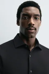 Camisa de manga larga, color celeste con finas rayas verticales blancas, cuello italiano y cierre frontal de botones.