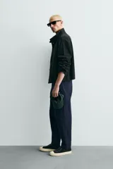 Pantalón de corte carrot fit confeccionado en tejido de algodón con estructura diagonal y efecto lavado. Presenta bolsillos frontales con bolsillo cerillero, bolsillos traseros de plastrón y cierre frontal con cremallera y botón.