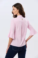 Camisa de lino color rosado, de manga tres cuartos terminada en volados, con cuello camisero clásico y canesú en la espalda con pliegue.
