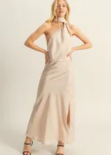 Vestido largo de satén color beige, con escote halter, espalda descubierta y tajo lateral en la falda.