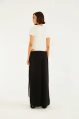 Pantalón negro de silueta amplia y caída relajada, con cintura elástica ajustable mediante cordón blanco y detalles de vivos laterales en color blanco.