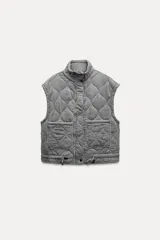 Chaleco gris acolchado con cuello alto, cierre frontal con cremallera metálica, bolsillos de plastrón en delantero y bajo ajustable con cordones.