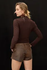 Short de cuero marrón con acabado desgastado, tiro bajo, presillas para cinto y bolsillos delanteros.