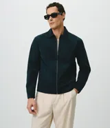 Campera Harrington de gamuza sintética color verde oscuro, de manga larga, con cuello camisero y cierre frontal completo.