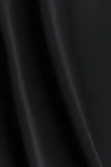 Pantalón negro de tiro alto, corte ancho y largo midi. Confeccionado en tejido de punto elástico con costuras verticales en el frente.