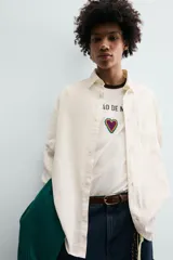 Camisa de corte relajado confeccionada en tejido con mezcla de lino. Presenta cuello solapa, manga larga con puños abotonados, bolsillo plastrón en el pecho y cierre frontal con botones. Incluye bordados a contraste en la espalda.