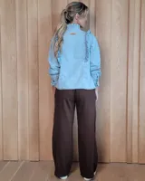 Pantalón de algodón color arena, de corte recto y holgado, con cintura elástica y detalle de costuras horizontales decorativas en la parte inferior de las piernas.