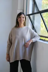 Sweater de punto con acabado brillante, color visón, de corte holgado y mangas largas con puños ajustados. Presenta un diseño con costuras verticales decorativas en el frente.