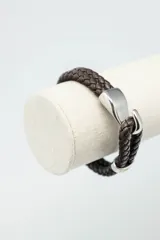 Pulsera de cuero trenzado color marrón oscuro con cierre de gancho metálico plateado.