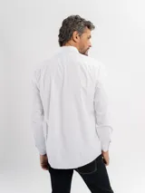 Camisa de manga larga color azul marino, confeccionada en algodón, con cuello abotonado y cierre frontal de botones.