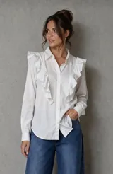 Camisa de popelina de algodón color blanco, con cuello clásico, cierre frontal de botones y volados decorativos en los hombros y el frente.