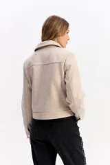Campera corta de paño color negro, con cierre frontal metálico, cuello camisero y bolsillos frontales con solapa y botón metálico.
