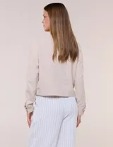 Camperita de tela liviana color beige, de silueta entallada con cuello a la base y abotonadura frontal con botones a tono. Cuenta con dos bolsillos con solapa en el frente, mangas largas con puños abotonados y largo a la cintura.