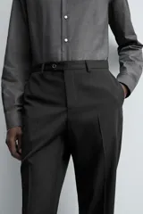 Pantalón de traje regular fit confeccionado en tejido de lana. Presenta bolsillos frontales, bolsillos traseros de vivo con botón y cierre frontal con cremallera y botón.