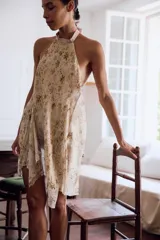 Top halter de tejido ligero con estampado floral en tonos tierra sobre fondo beige. Presenta diseño sin mangas, espalda descubierta y cierre con lazadas en el cuello y la espalda, con un bajo asimétrico.