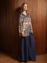 Camisa de seda de corte clásico y largo, con estampado paisley en tonos azules, marrones y beige. Presenta cuello camisero, cierre frontal con botones y mangas largas con puños rectos.