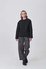 Campera acolchada de diseño capitoneado con patrón de rombos, color negro, de corte holgado, manga larga y cierre frontal con botones a presión.