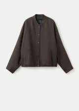 Chaqueta bomber oversize color verde oscuro con cuello mao, manga larga y cierre frontal de botones a presión.