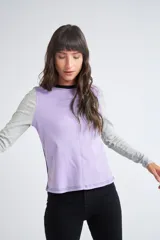 Remera de manga larga con diseño color block, combinando panel frontal en color lila, mangas en gris melange y espalda en negro. Presenta cuello redondo y costuras a la vista.