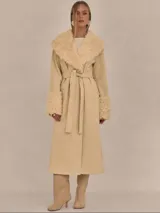 Abrigo trench maxi color beige con ribete de piel sintética en cuello y puños.