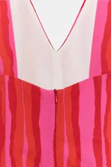 Vestido largo sin mangas con escote en pico y tirantes anchos. Presenta un diseño de rayas verticales en tonos fucsia y rojo, con detalle de falsos botones frontales y cierre de cremallera oculto en la espalda.
