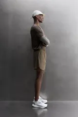 Short de running 2 en 1 color beige, confeccionado en tejido técnico ligero y elástico con malla interior integrada. Presenta cintura elástica ajustable con cordón, bolsillo trasero con cierre y aberturas laterales en el bajo.