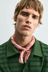 Polo de manga larga con cuello solapa y cierre frontal de botones. Presenta un tejido jacquard texturizado con rayas horizontales en tonos de verde.
