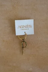 Aro individual con dije de letra en bronce con acabado rústico y texturizado, montado sobre una argolla metálica dorada.