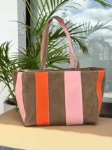Bolso tipo shopper de diseño amplio, confeccionado en gamuza con un patrón de franjas verticales en tonos marrón oscuro, rosa y verde oliva. Cuenta con doble asa de hombro y cierre superior.