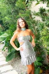 Vestido corto negro con diseño cut-out en la cintura, estilo strapless y ruedo decorado con flecos largos.