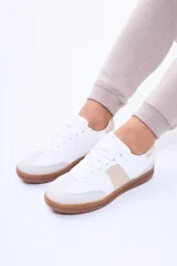 Champion de estilo urbano, color blanco con detalles en beige y suela de goma color caramelo. Presenta un diseño de líneas limpias con refuerzos en la puntera y laterales.