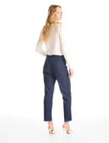 Pantalón tipo jegging de tencel en color azul oscuro, con pretina ancha elástica, bolsillos simulados en la parte delantera y bolsillos aplicados en la parte trasera. Presenta un corte al tobillo con ruedo desflecado.