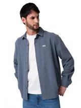 Camisa de manga larga con textura tipo waffle, color gris azulado. Presenta cuello camisero, cierre frontal con botones perlados, puños abotonados y un bolsillo en el pecho con etiqueta de la marca.