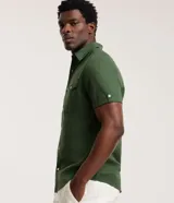 Camisa comfort masculina de lino y algodón color marrón, con cuello inglés, mangas cortas con vuelta, cierre frontal por botones y un bolsillo en el pecho.