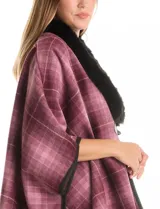 Ruana de tejido suave, color beige y marrón con estampado geométrico repetitivo. Posee cuello con aplique de piel sintética marrón y ribetes negros. Se combina con un suéter marrón de manga larga con botones en el puño.