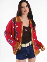 Campera tejida en jacquard con cierre frontal, cuello tipo polo y bolsillos delanteros. Diseño multicolor con estampado geométrico de rombos y detalles bordados a mano.