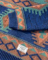 Buzo tejido de punto con diseño geométrico de estilo étnico. Presenta cuello redondo, puños y ruedo acanalados. Confeccionado en una mezcla de lana y fibras sintéticas, con etiqueta de marca en el pecho y en el ruedo.